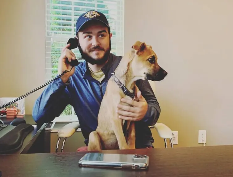Person on the telephone with a dog sitting in their lap